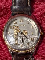 Close-up of watch face with golfer motif and Roman numerals