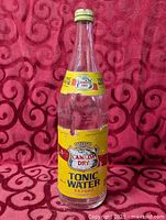 Full view of 12.5" Canada Dry Tonic Water glass bottle with yellow label and cap