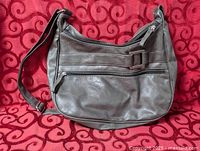 Full view of leather shoulder purse on patterned background