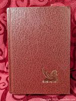 Front cover maroon textured hardcover with gold Pegasus logo