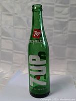 Full view of vintage green glass 7 Up bottle with label and markings