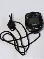 Image of front of electronic stopwatch with neck cord attached, black color, brand visible