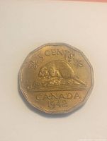Obverse image of 1942 Canadian 5 cent coin showing beaver on rock with maple leaves, '5 CENTS', 'CANADA', and year '1942'.