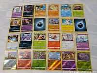 Wide view of approximately 30 Pokémon cards laid out in rows showing the front of the cards including holo and non-holo types.