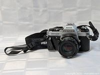 Front and side view of Pentax Super Program 35mm film camera with lens and strap attached on plain background