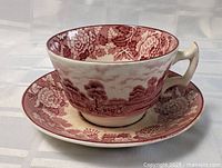 Antique Woods and Sons teacup and saucer set showing detailed floral and countryside pattern in reddish color on white ceramic background.