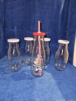 Front view of all five glass bottles showing lids and Christmas bottle with straw