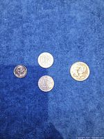 Four coins on blue fabric showing denominations 5c, 10c, 10c, 20c