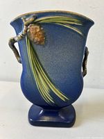 Front view of vase showing pine cone and needles relief