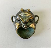 Top view showing grotesque devil face with hollow oval mouth and two side loops.