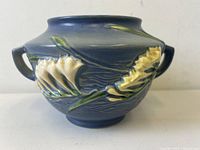 Side view of blue Roseville jardiniere with yellow freesia flower relief