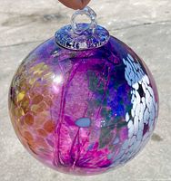 Close-up front view of the spherical glass suncatcher showing purple glass with amber, white spots