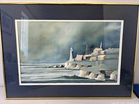 Framed watercolour painting of a maritime lighthouse and cliffs, shown head-on to capture entire artwork and matting.