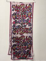 Full view of the long rectangular scarf with colorful woodland floral patterns hung on a hanger.