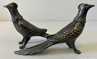 Side view of two silver plated pheasant-shaped salt and pepper shakers showing detailed feather design and form.