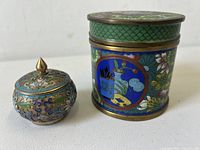 Both cloisonne enameled brass lidded boxes side by side showing size difference and colorful decorations.