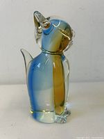 Side view of the vintage mid-century modern blown glass cat figurine showing pointed ears, curled tail, and gradient blue to amber coloration.