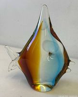 Front view of angelfish glass paperweight showing blue, amber, and green hues with clear glass fins and rounded form.