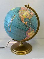 Globe showing North and South America with power cord attached to base indicating illumination feature.