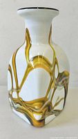 Side view of the vase showing the rippled amber and white patterns inside clear glass, the rounded neck, flared rim with a dark edge.