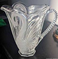 Side view of clear and frosted crystal glass swan pitcher showing etched feather texture and twisted neck handle.
