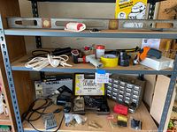 Three shelves containing a large assortment of tools including a large carpenter's level, tape tools, multiple bins with assorted small parts, a Black & Decker corded drill, and the Weller Expert soldering kit.