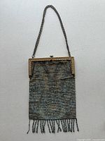 Front view of antique beaded purse showing metal frame, chain handle, and beaded fringe.