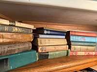 Shelf of antique books showing worn cloth and leather bindings, title spines include Adventures of Huckleberry Finn and others.