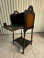 Side view of the antique wood smoking stand table showing the open metal-lined compartment and pipe resting on top.