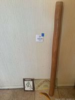 Photo showing the didgeridoo standing against wall with two boomerangs and a boomerang instruction book on floor.