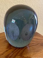Front view showing two large etched eyes on the dark smoky glass paperweight.