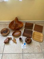 Photo showing all items in lot, including large hand carved basket with handle, various bowls, rectangular plates, coasters, Tuscan box, and candle holder.