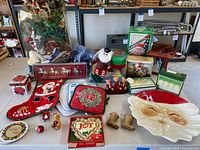 Wide shot of the collection showing all items including ceramic Santa platter, felt stocking, various boxed ornaments, figurines, pot holders, and holiday ribbons.