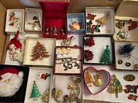 Overall view of assorted Christmas jewelry including pins, brooches, earrings, and a Santa face pin