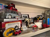 Shelf with various Ford classic car models, an award shaped like a vintage telephone, multiple memorabilia items, plaques, and collectible cards arranged together.