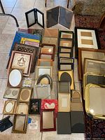 Wide view showing multiple picture frames ranging in size and style, along with four sealed photo albums in blue and red packaging.