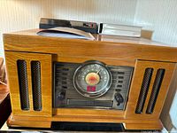 Front view of Crosley CR72 entertainment center showing the radio dial, speaker grills, and control knobs on the wooden cabinet.
