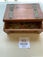 Wooden box open showing assortment of coins inside, also showing box size relative to auction card