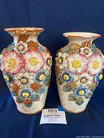 Front view of two English Majolica vases with applied floral decoration showing overall condition and style.