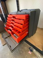 Flambeau 22060 toolbox with six orange pullout drawers opened, showing compartments with various tools inside.