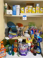Shelf with cleaning supplies, food storage bags, rolls of paper wraps, and E-Z Movers furniture slides