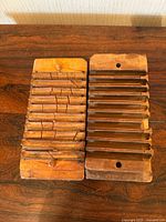 Top view of two wooden cigar molds side by side on a wooden surface, showing the parallel grooved metal strips used for pressing.