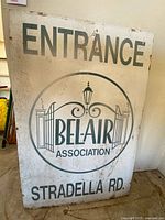 Front side of metal sign showing 'ENTRANCE', 'BEL-AIR ASSOCIATION', and 'STRADELLA RD.' text with gates and lantern logo.
