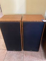 Pair of Fisher speakers, front view with black fabric grills and wood veneer cabinets.