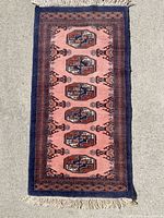 Top view of the small rectangular floor rug laid on a concrete surface showing full rug with intricate geometric medallion design in warm tones.