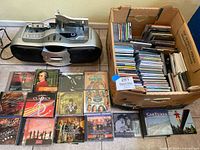 Sony CFD-F10 stereo unit and large box of assorted music CDs with some CDs displayed outside the box.