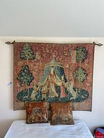 Full view of vintage tapestry mounted on wall above bed with two matching pillows on bed