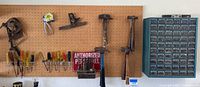 Wide view of tools arranged on pegboard including hammers, screwdrivers, level, and hanging tool parts caddy with blue storage bins