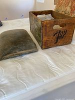 Wooden crate with seat cushion cover placed next to it on a bed