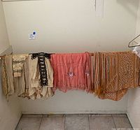 Vintage beaded dresses hung on a rod against a studio wall showing multiple colors and beadwork